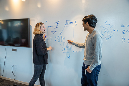 Two AI2 employees collaborating in front of a whiteboard.